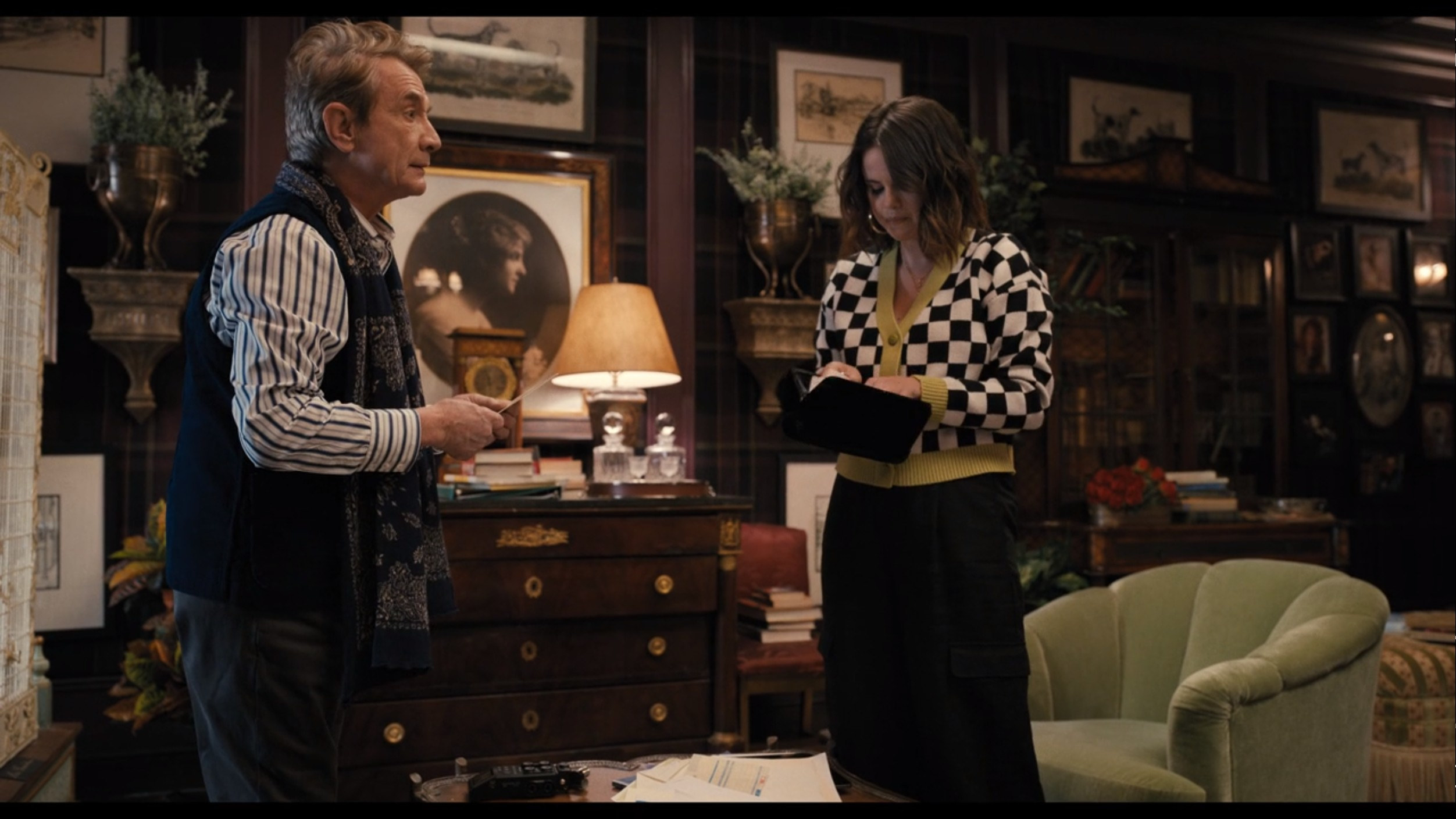 Mabel standing with Oliver in a checkered cardigan with green accents